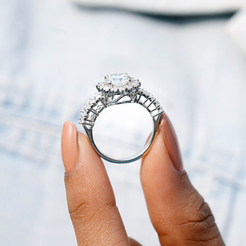Silver ring with a large diamond held by a hand against a blurred background