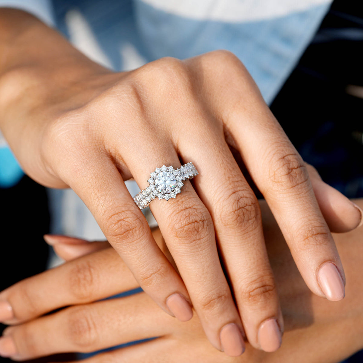 Close-up of a hand wearing a diamond ring with a blurred background